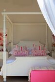 Himmelbett mit weißem Holzgestell und pink-weiss gemusterten Kissen
