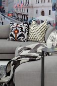Patterned scatter cushions on pale grey sofa in front of New York mural wallpaper