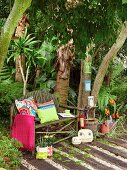 Rustikale Bank aus Ästen und Accessoires unter Baum im Garten