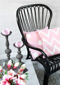Black wicker chair with pink cushions and grey candlesticks