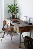 Vintage chair with wooden shell seat at desk with potted house plant in corner