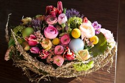 Easter arrangement in wicker basket with half-moons of hay & spring flowers