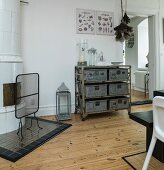 Antique, white tiled oven and shelving on castors with metal boxes in dining room of period apartment