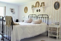 Twin beds with black metal frames pushed together against wallpapered accent wall in vintage-style bedroom