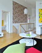 Loungebereich mit rundem weißem Beistelltisch und farbige Kissen, großformatiges modernes buntes Bild über Treppenabgang