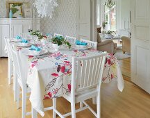 Table festively set with floral tablecloth in white dining room