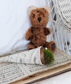 Pot of moss in sheet music cone next to teddy bear