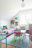 Play table and colourful chairs on rug with animal motif in front of bed with patchwork counterpane in child's bedroom