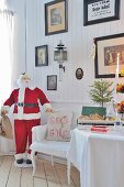 Nikolausfigur und Kissen mit schwedischem Weihnachtswunsch auf Armlehnstuhl; historische Bilder an holzvertäfelter Wand
