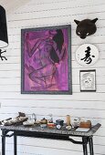 Modernes, violettes Bild und Wanddeko über Konsolentisch mit Erinnerungsstücken