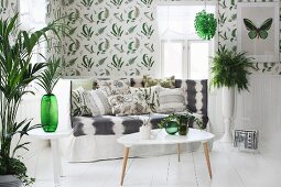 Coffeetable in 50er Jahre Stil vor Sitzbank mit Lehne in ländlichem Wohnzimmer mit dekorativen Grünpflanzen