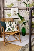 Grass-patterned cushion on bamboo chair in front of green floor vase in front of half-timbered wall with leaf-patterned wallpaper panels in vintage ambiance