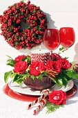 Festive arrangement in red with roses & candle in glass bowl