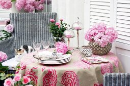 Tisch auf Terrasse dekoriert mit rosafarbenen Rosen & Bauernhortensien