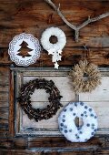 Hand-crafted, decorative Christmas wreaths made from various materials hanging on rustic facade of wooden cabin