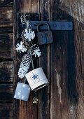 Pine cones dipped in white paint and painted cans hung on rustic cabin door as Christmas decorations