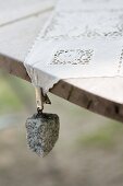 Tablecloth weight with granite pebble hung from lace tablecloth