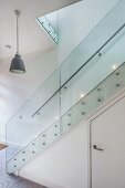 Modern staircase with glass balustrade; storage space with door below