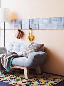 Two-seater pastel sofa on brightly patterned rug below square textured pictures on wall