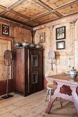 Antique, farmhouse furniture and religious pictures in artistically wood-panelled dining room