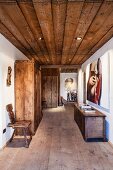 Contemporary art and antique, rustic hall furnishings (plank chair, wardrobe and trunk) in hallway