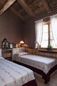 Textile wallpaper with geometric pattern in attic guest room with twin beds and romantic ambiance in restored chalet