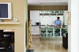 Man behind counter in open-plan kitchen with walls painted sandy beige