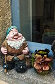 French garden gnome and vase decorated with applied ceramic flowers on windowsill