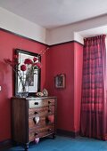 Chest of drawers with heart-shaped pendants and bouquet against dusky pink wall and colour-coordinated curtains in window niche