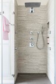 A floor-level, tiled shower with a rain head, a hand-held shower head and wall mounted jets