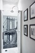 Wallpaper mural with bridge motif as back wall of shower and framed black and white photos on side wall