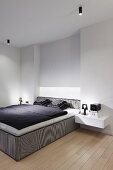 Minimalist bedroom with box-spring bed, black and white bed linen and floating bedside cabinets