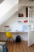 Yellow classic chair in workspace with floating desk and shelves under sloping ceiling