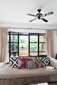 Ceiling fan above couch with geometric scatter cushions in front of open terrace doors
