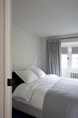 Blick durch offene Schiebetür auf Doppelbett in grau-weisses Schlafzimmer