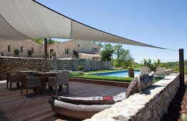 View across wooden terrace with awning and adjoining pool too traditional house in southern France