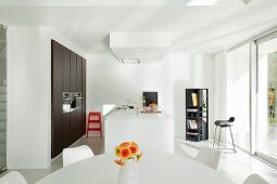 Blick über Essplatz auf Designerküche mit Küchentheke und eingebautem Schrank