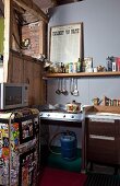 Herd mit Gasflasche und 60er Jahre Kühlschrank mit Aufklebern in rustikaler Loftküche