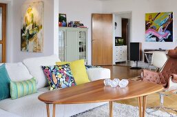 Sofa mit Dekokissen, Holztisch und Ledersessel in offenem Wohnraum