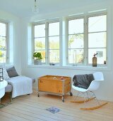 White, designer rocking chair and vintage toy box on castors in minimalist, Scandinavian interior