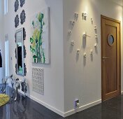 Eckwand in offenem Wohnraum mit Wanduhr, Gemälde mit Blumenmotiv und Spiegel auf Doppelreihe stilisierter Blüten