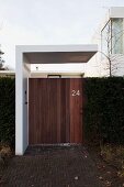 Zeitgenössisches Wohnhaus mit minimalistischem modernem Dach über Gartentor in Holzoptik