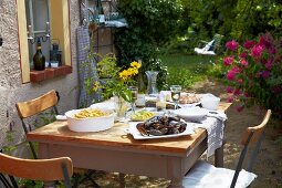 A wooden table in the garden ofa French country house laid with mussels, chips and lemon slices