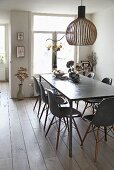 Designer lampshade made from birch above dining table with polished concrete top and shell chairs in dining room