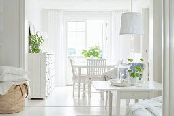 Open-plan, white, shabby-chic interior with green houseplants