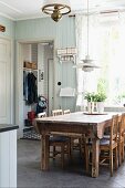Rustic dining area with solid-wood table and chairs below pendant lamp in country-style kitchen