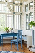 Dining area with blue-painted chair and table in rustic loggia