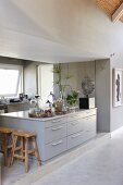 Pale grey island counter with drawers in open-plan designer kitchen