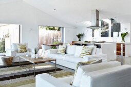 weiße Sitzgarnitur mit Kissen um filigranen Couchtisch, auf Streifenteppich in modernem Wohnzimmer
