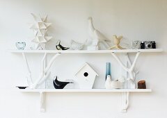 Various china birds on white wall-mounted shelves on white wall